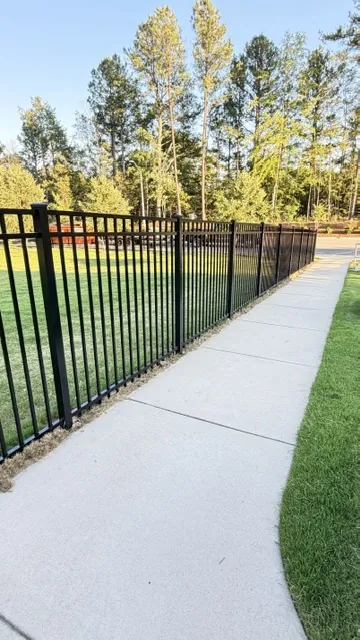 Black aluminum commercial fence running along a paved walkway, installed by Superior Fence & Rail of Raleigh