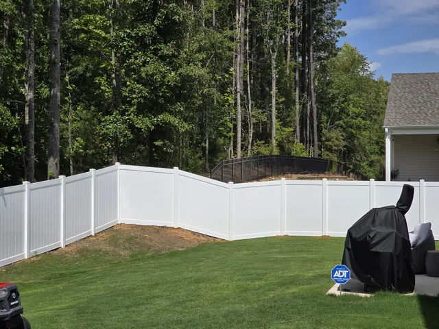 White vinyl privacy fence along a wooded back property line, installed by Superior Fence & Rail of Raleigh