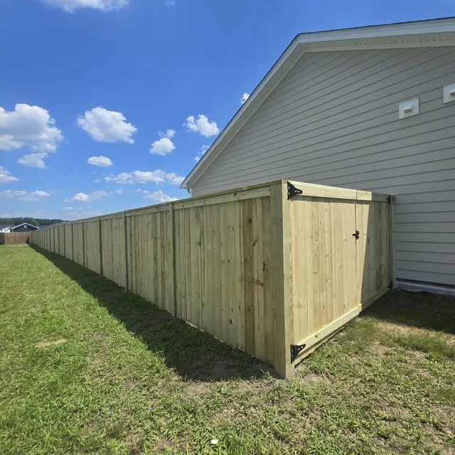 Pressure-treated wood privacy fence with a double drive gate beside a home, installed by Superior Fence & Rail of Raleigh